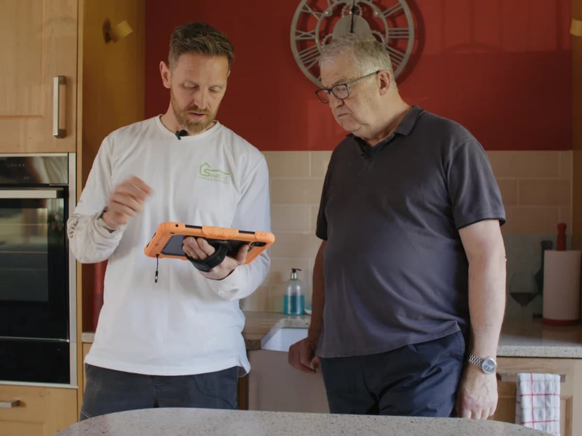 A Heat Geek installer going through the design with a homeowner in their kitchen
